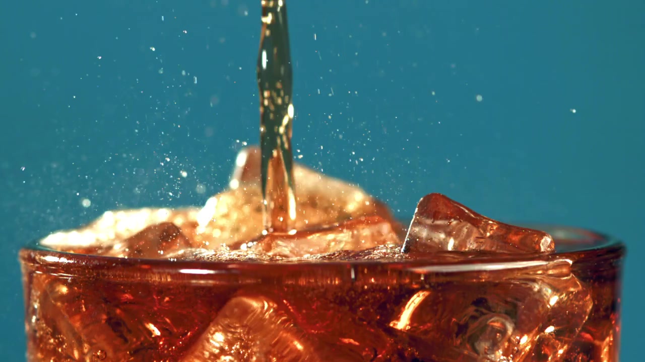 Cola rinfrescante versata su cubetti di ghiaccio al rallentatore