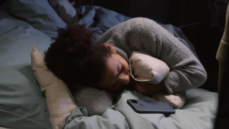 Mujer joven abrazando una almohada y recostada en el dormitorio.