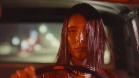 young woman with hair blowing in wind driving through city streets
