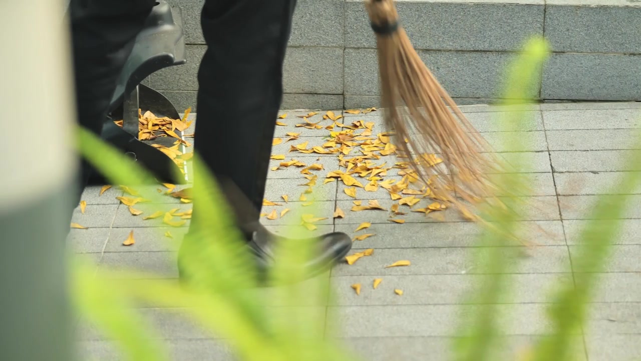 Uomo che spazza foglie autunnali con scarpe robuste a Metro Manila, Filippine