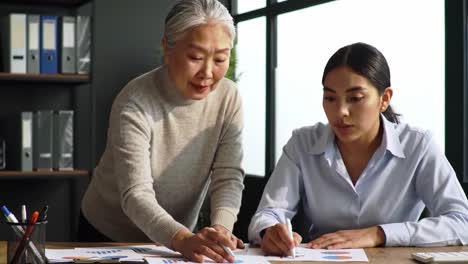 two business professionals review marketing strategies in a bright, modern office. they analyze charts and graphs, discussing ideas and noting key points for improvement.