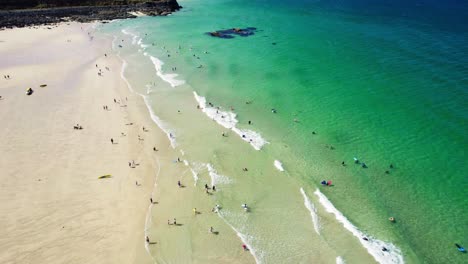 porthmeor beach in st ives with tourists enjoying the turquoise waters along the cornish coastline during summer