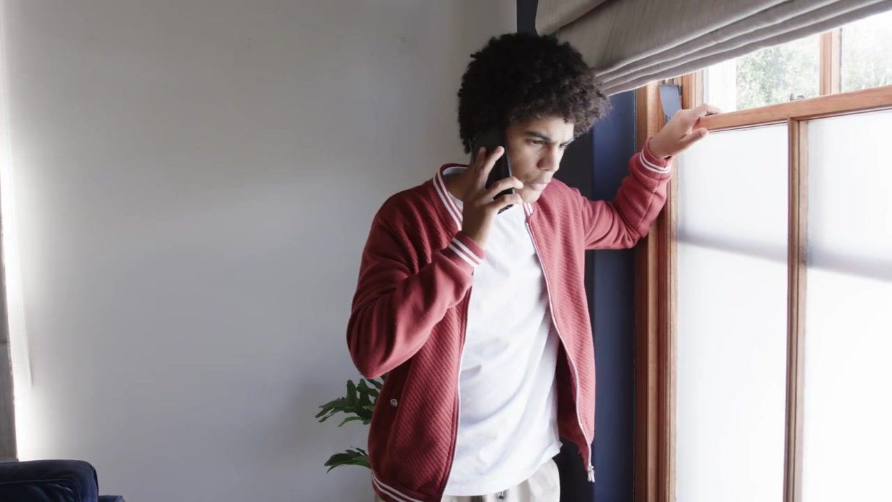 Mand med telefon bevæger sig mod vinduet, mens en scanningslinje toner frem, justerer persiennerne og tjekker udenfor for teknologi.