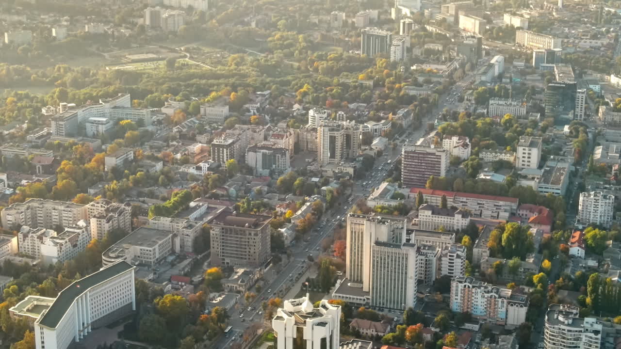 Aerial drone view of Chisinau downtown at sunset. Panorama view of multiple buildings, Parliament, Presidency, roads with moving cars and lush trees. Moldova