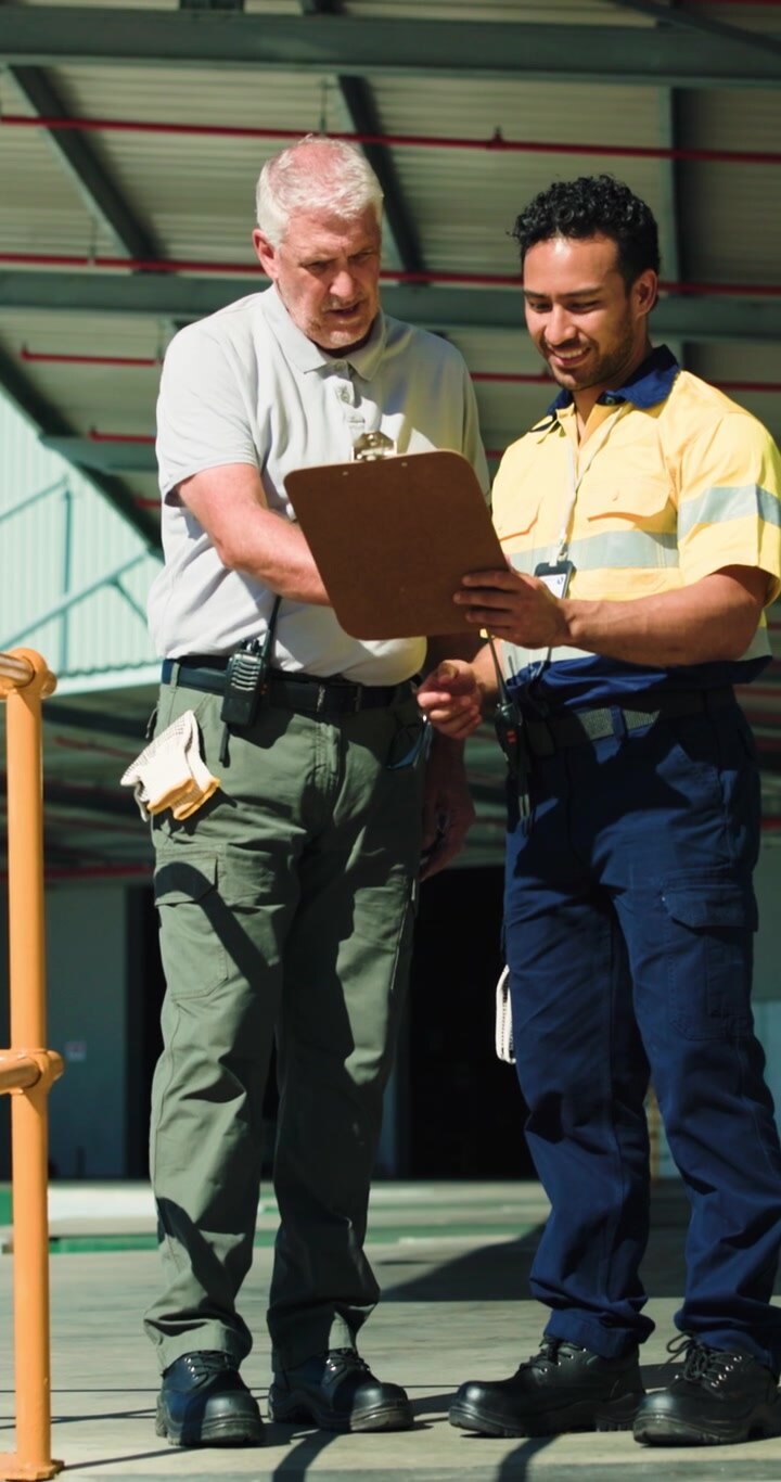 Two Industrial Workers Reviewing Documents on a Clipboard