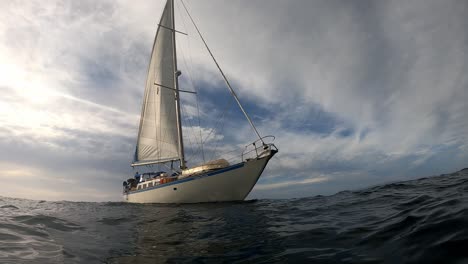 White-Sailboat-Sailing-In-Deep-Calm-Waters---tilt-up-shot