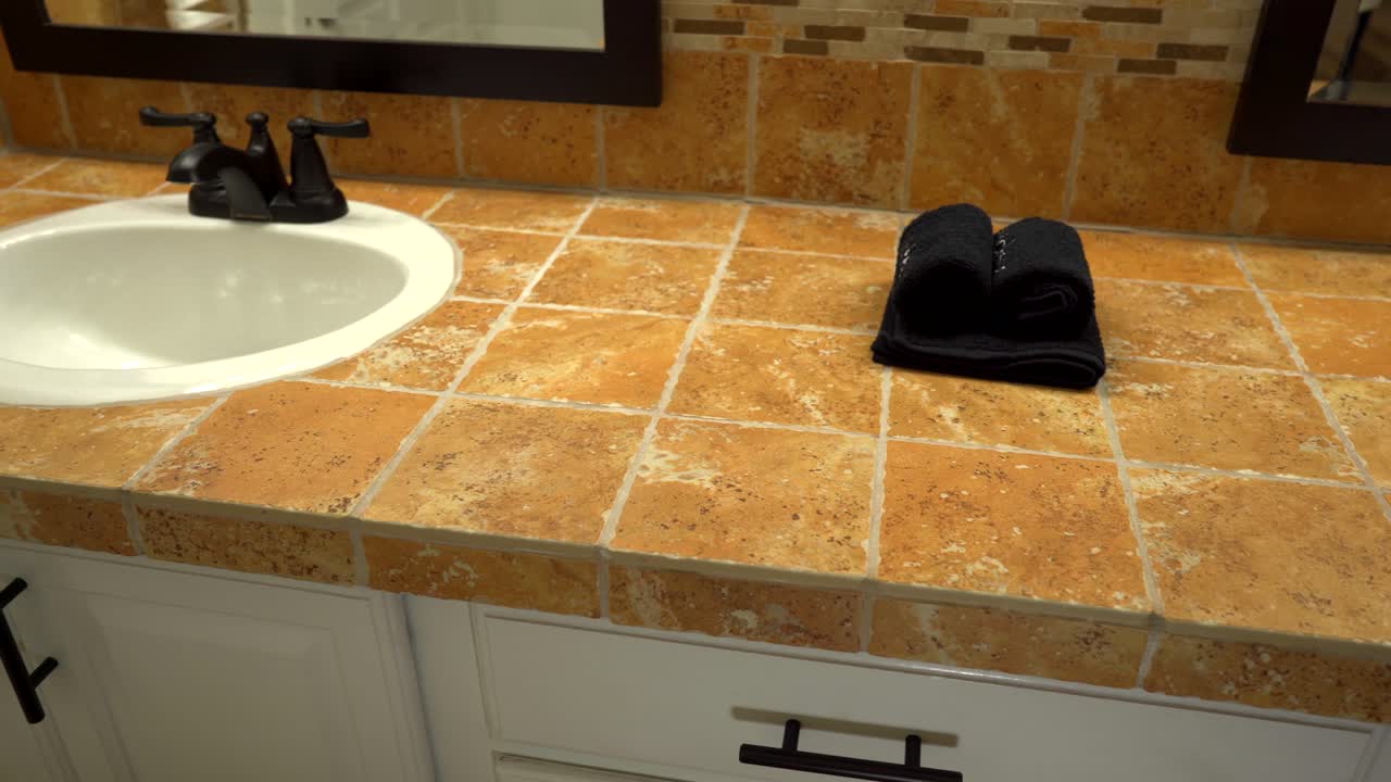 lavabos de baño con grifos de color marrón oscuro y encimera de mosaicos y placa para salpicaduras
