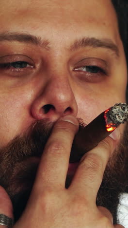 brutal serious man in studio. brutal caucasian serious hipster sitting and smoking cigar