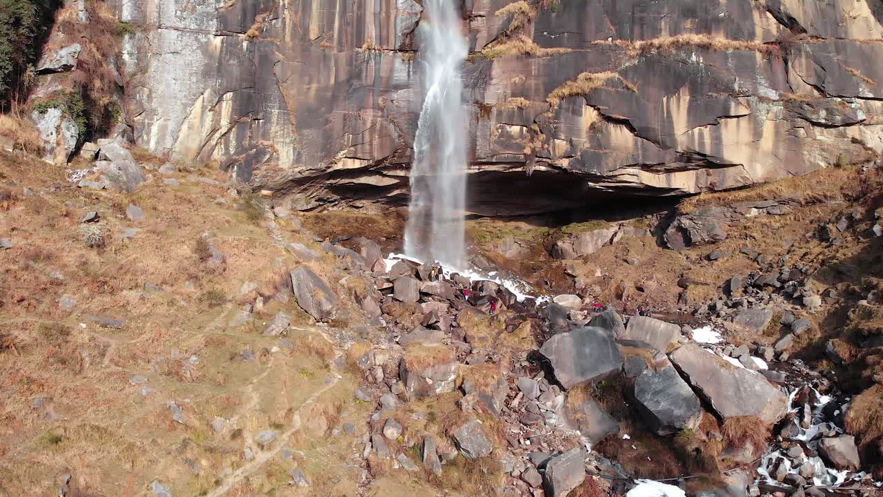 toma aérea de sobrevuelo de personas jugando cerca de las cascadas jogini cerca de manali, himachal pradesh durante el invierno filmada con un dron en 4k