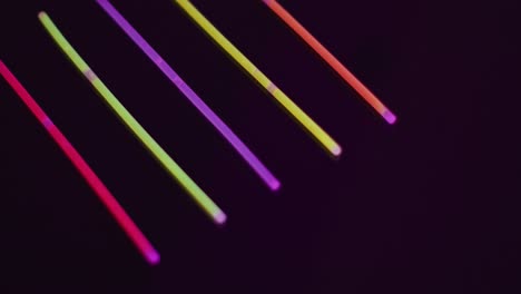 animación de cinco palos de brillo de neón de colores sobre fondo negro con espacio de copia