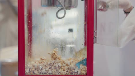 freshly popped popcorn being scooped in a classic red popcorn machine