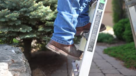 man climbs a ladder on a job site to repair a roof