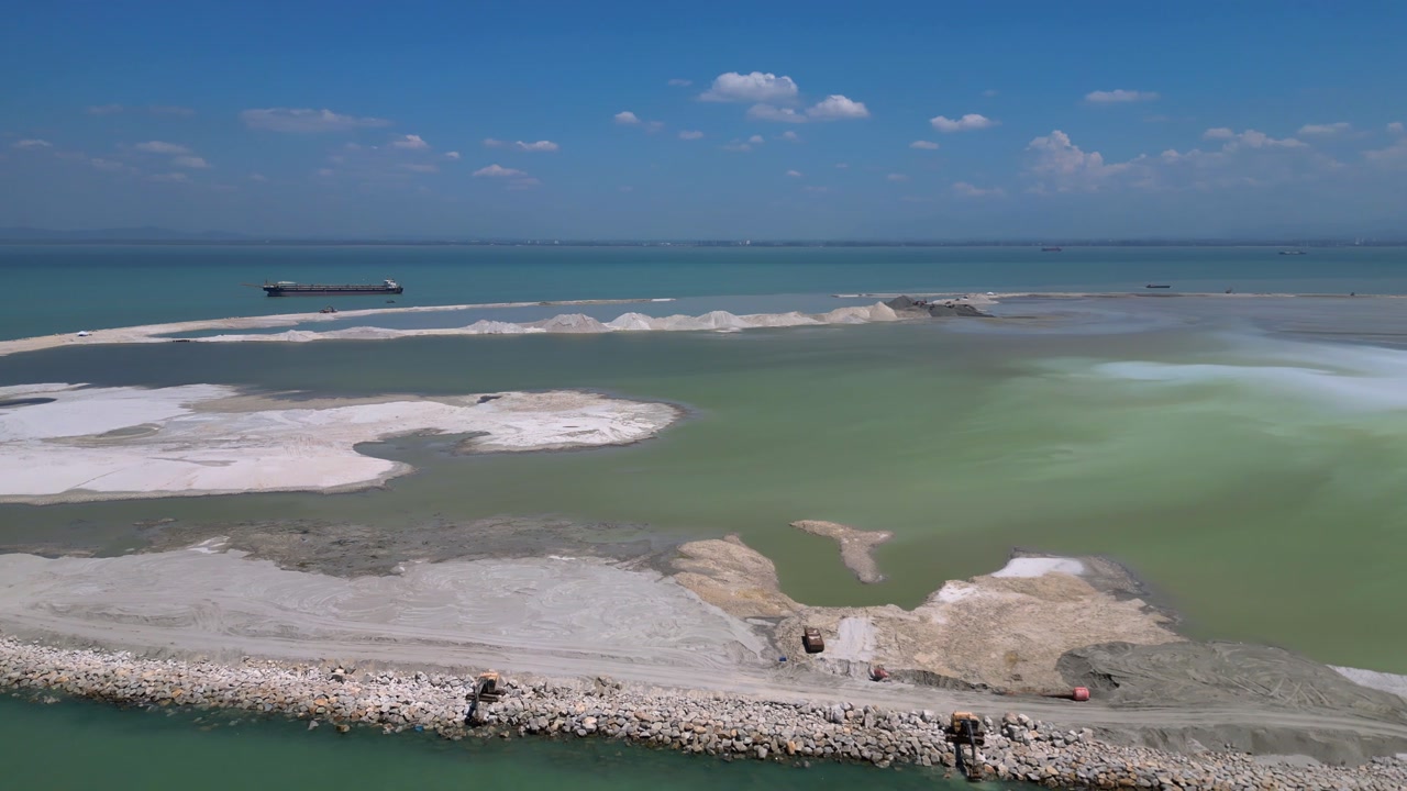 Land reclamation project in Penang creating new land from the sea, showing environmental impact and coastal urbanization. Smooth aerial view drone shot panorama from above
