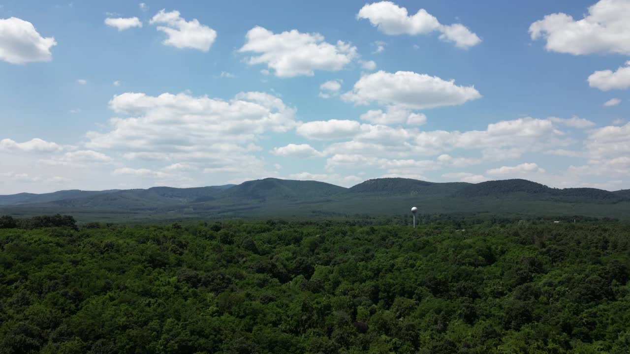 Aerial hyperlapse of clouds on a sunny day - approaching the hills of B&ouml;rzs&ouml;ny, Hungary - water tower sphere in the forest