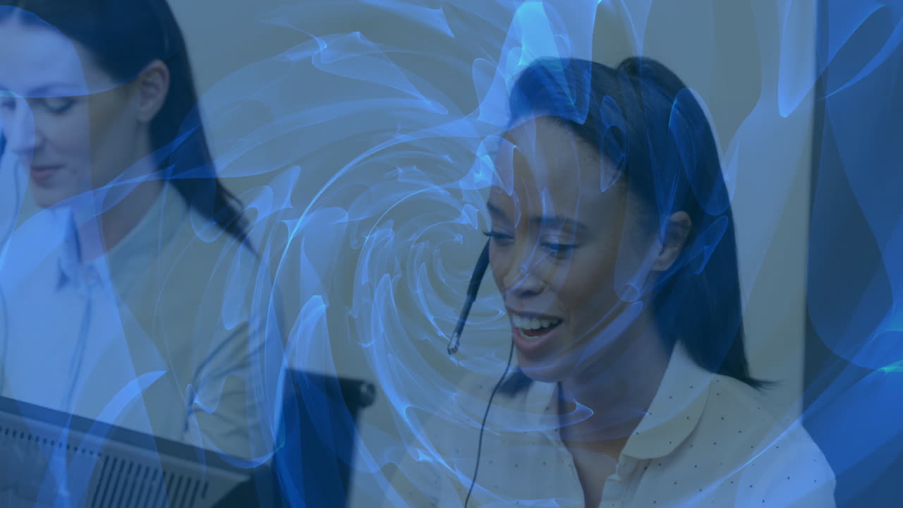 Smiling woman with headset working at computer over swirling blue animation
