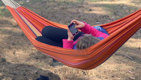 Mädchen-In-Der-Hängematte-Mit-Smartphone.-Junge-Frau,-Die-Mit-Dem-Mobiltelefon-Im-Internet-Surft