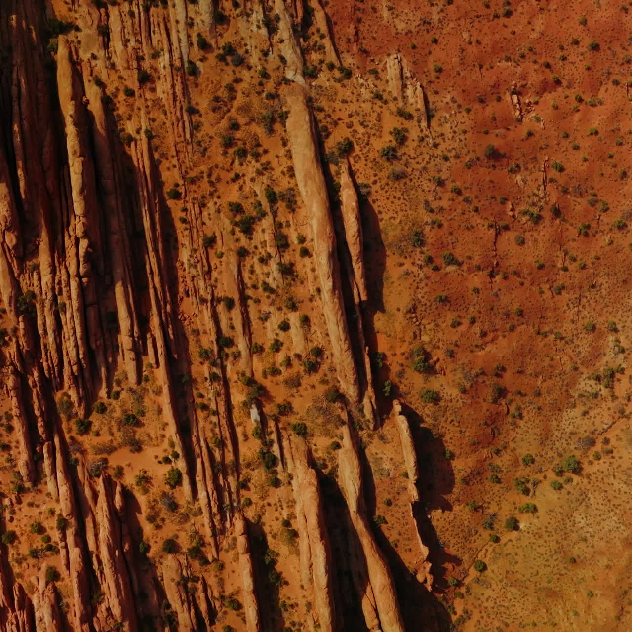 Un'auto che percorre la strada parallela alle montagne dalla forma insolita. Arido paesaggio color arancio del deserto nello Utah, USA, visto dall'alto