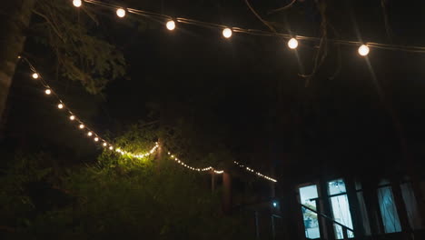 iluminado con guirnaldas patio por la noche. edificio de campo para los turistas para relajarse entre el denso bosque de naturaleza intacta. alojamiento moderno para vacaciones