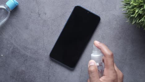 cleaning a smartphone with disinfectant spray