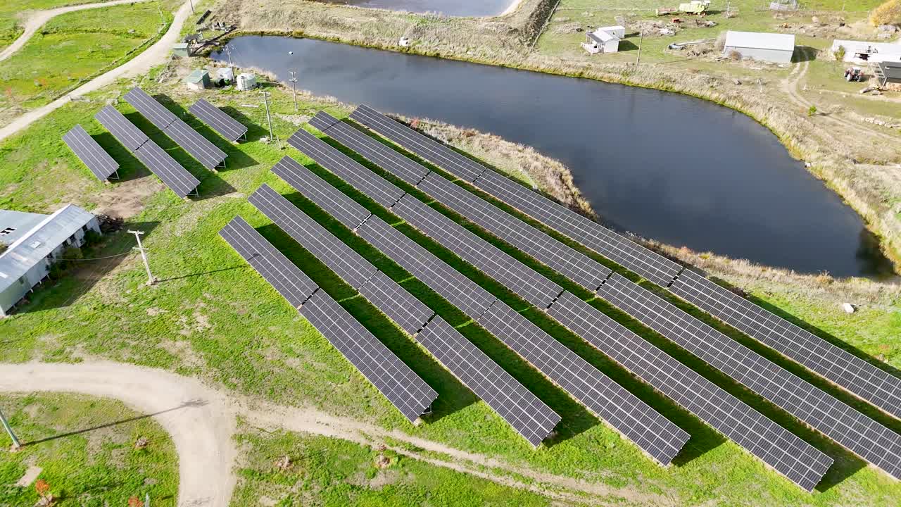 Drone footage captures expansive solar panels near a water body in Cromwell, showcasing renewable energy in a rural setting