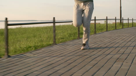 Frau-In-Sportkleidung,-Die-Morgens-Bei-Sonnenuntergang-Entlang-Der-Uferpromenade-Der-Stadt-Läuft-1