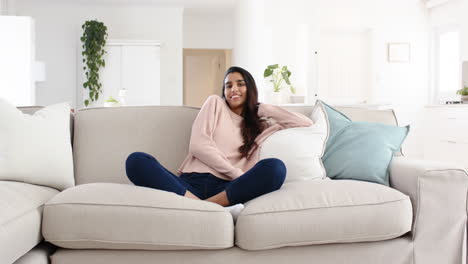 smiling woman relaxing on cozy sofa at home, enjoying peaceful moment