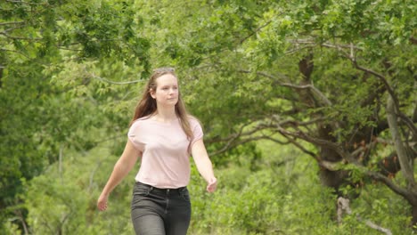 beautiful brunette girl walking in forest on sunny day