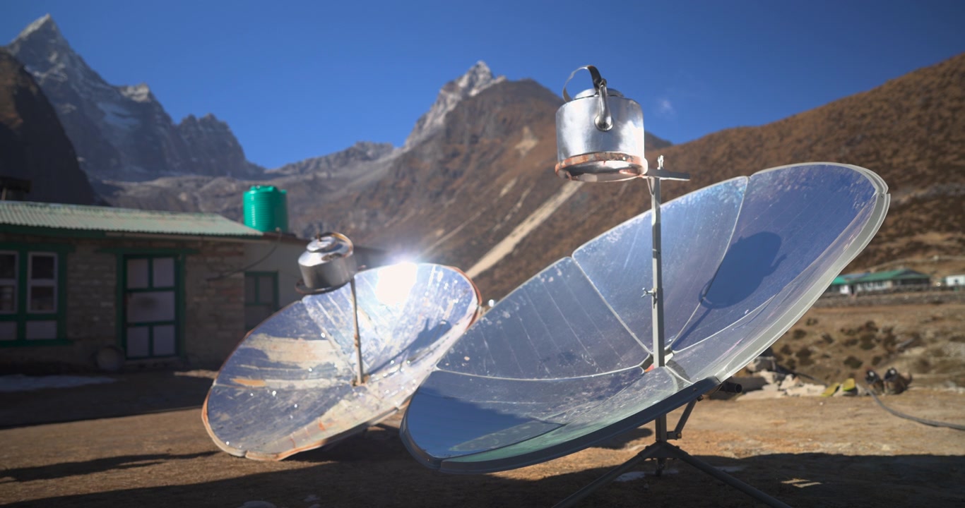 Et statisk nærbillede af parabolske solkomfurer, der koger vand i kedler ved en højtliggende bjerghytte i Namche Bazaar, Everest, Nepal.