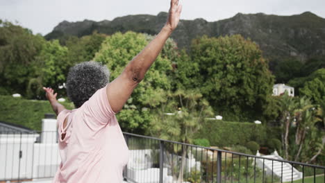 mujer afroamericana de edad avanzada concentrada practicando yoga de pie en el balcón, espacio de copia, cámara lenta