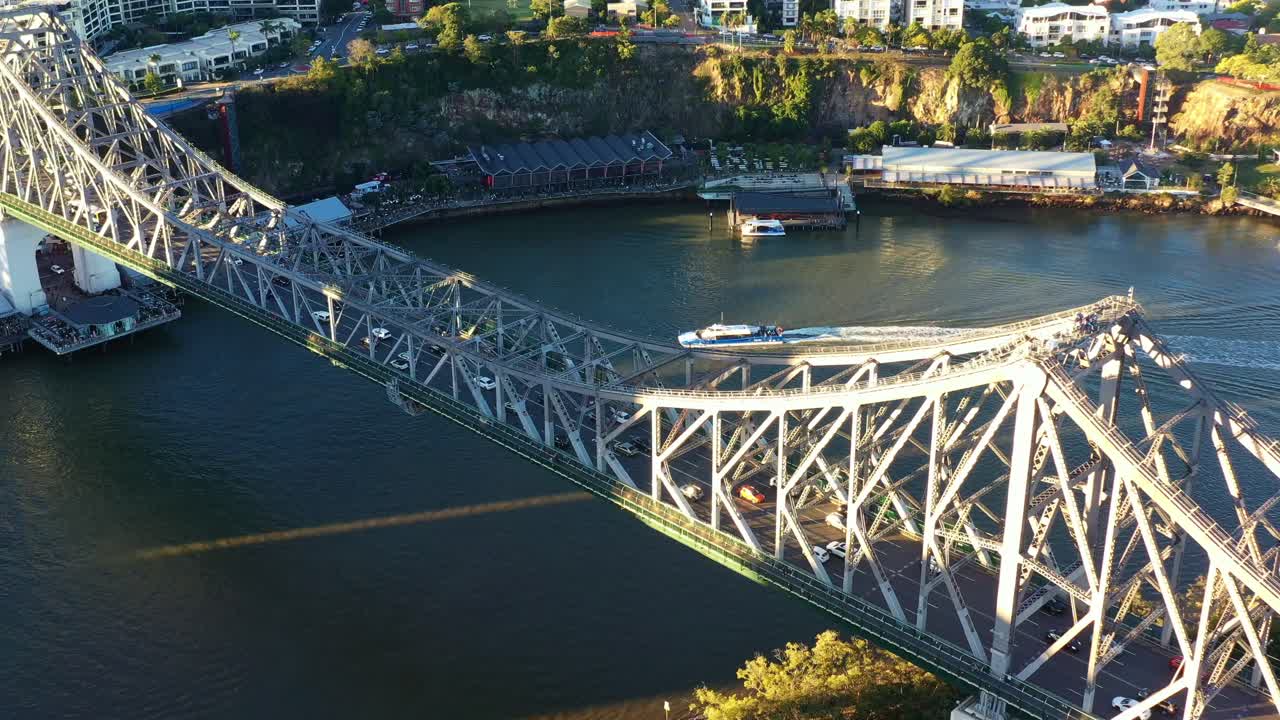 Cinematic birds eye view drone flyover Brisbane river capturing cars crossing iconic landmark Story Bridge between Fortitude Valley and Kangaroo Point inner city suburbs at sunset golden hours