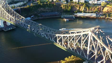 Cinematic-birds-eye-view-drone-flyover-Brisbane-river-capturing-cars-crossing-iconic-landmark-Story-Bridge-between-Fortitude-Valley-and-Kangaroo-Point-inner-city-suburbs-at-sunset-golden-hours
