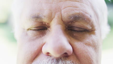 retrato en primer plano de un anciano biracial al aire libre abriendo y cerrando los ojos