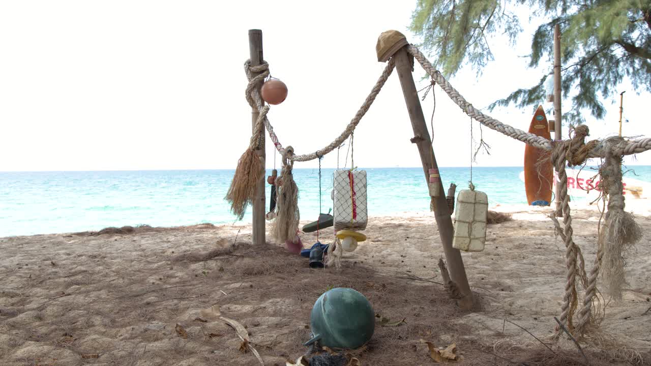 Inquadratura media statica di galleggianti da pesca colorati e corde appesi su una spiaggia tropicale soleggiata