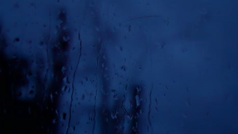 gotas de tormenta lluviosa en la noche, mal humor caen por el cristal de la ventana closeup bokeh
