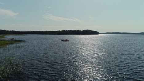 Floating-party-barge-on-vast-lake-water,-aerial-drone-view