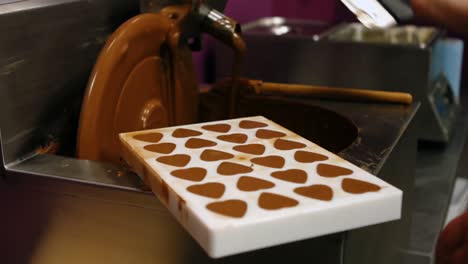 worker filling mould with melted chocolate