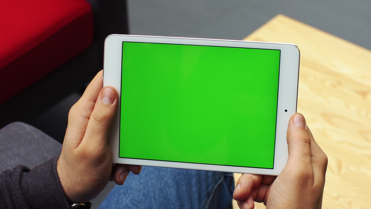 Tablet with green screen held by hands