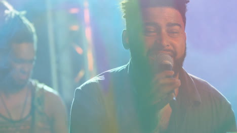 male vocalist leaning into microphone under colorful stage lights, displaying animated audio waves