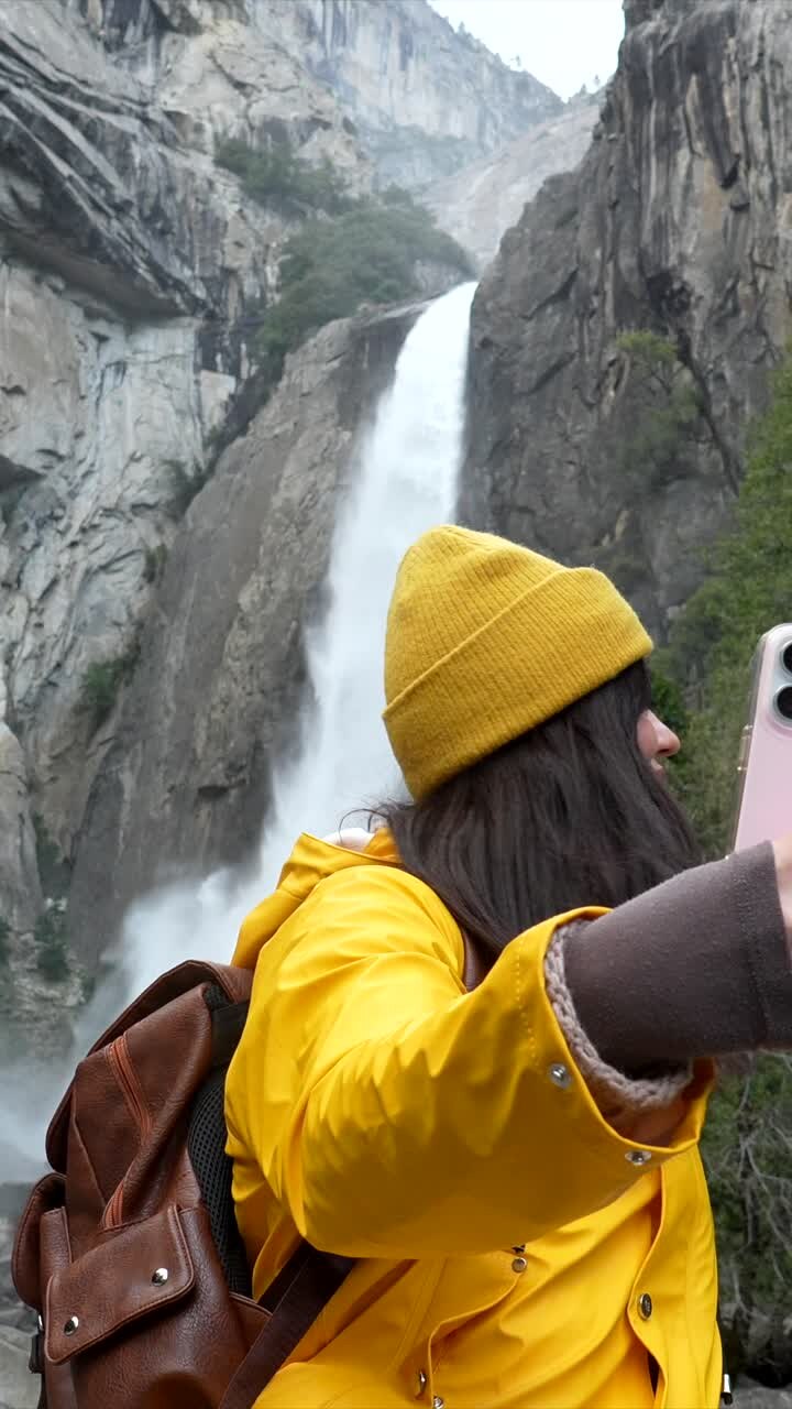 Joven grabando un video selfie frente a una majestuosa cascada