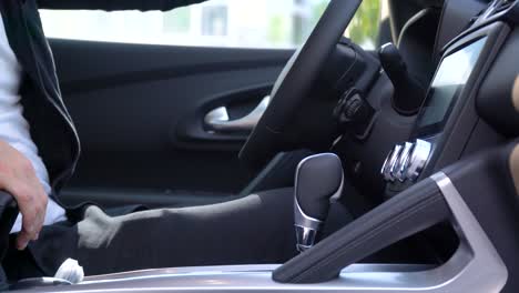 el hombre de negocios controla a mano la transmisión de cambio en un coche de lujo.