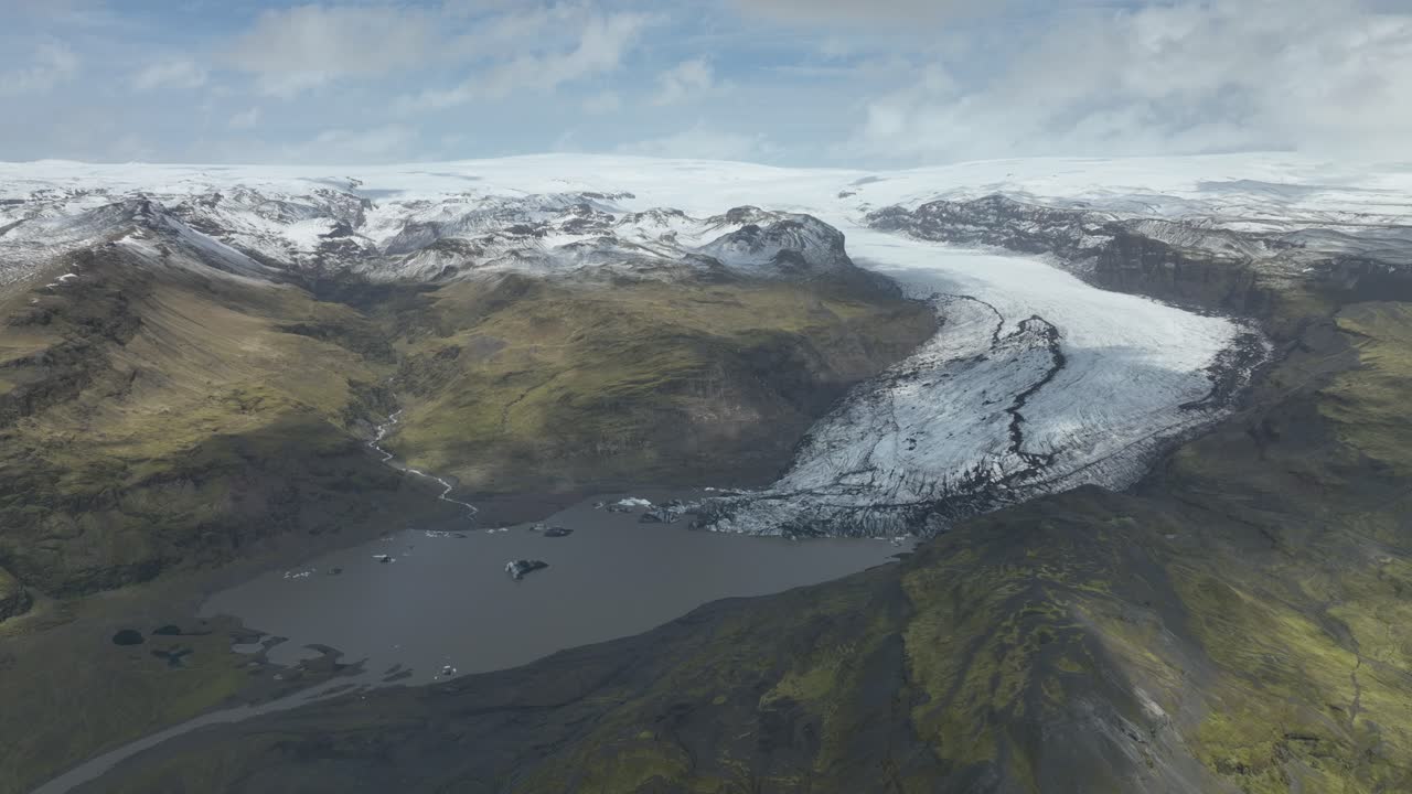 아이슬란드에서 눈 인 산과 푸른 계곡으로 둘러싸인 빙하로 흘러들어가는 솔헤이마요쿨 빙하의 드론 뷰