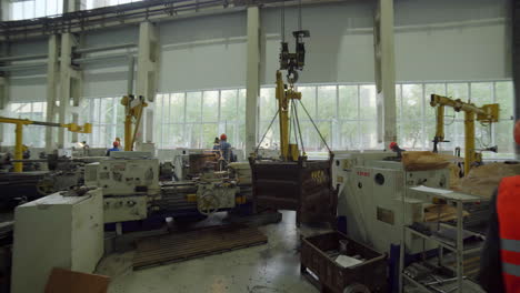 factory workers moving heavy equipment using crane