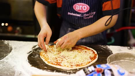 chef prepares pizza with cheese and tomato sauce