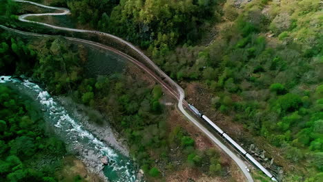 drone shot of train traveling through norway's forested mountains