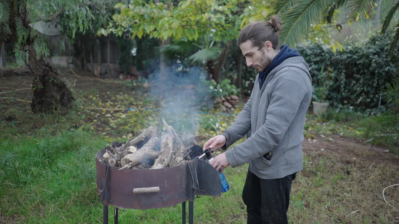 Man lighting a wood fire in a grill