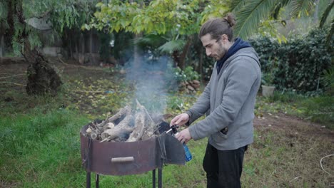 man lighting a wood fire in a grill
