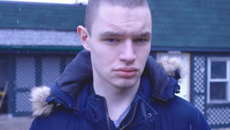 A-Man-Wearing-Winter-Coat-Looking-Straight-To-The-Camera-With-Falling-Snow-In-Canada---Close-Up-Shot