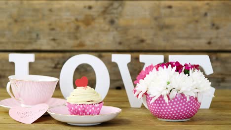 cupcake, tea, flower vase and happy mothers day greetings card in tray