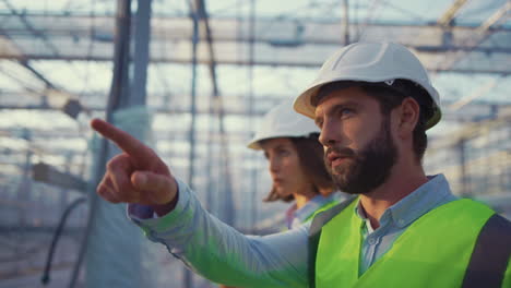 supervisores de la fábrica de uniforme hablando de vacío complejo de invernadero usando cascos