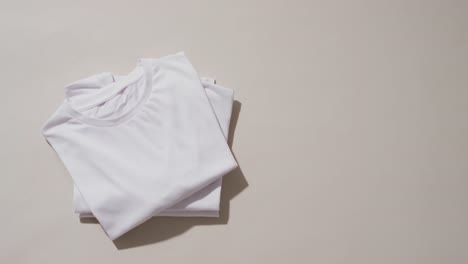 Video-of-stack-of-folded-white-t-shirts-with-copy-space-on-white-background